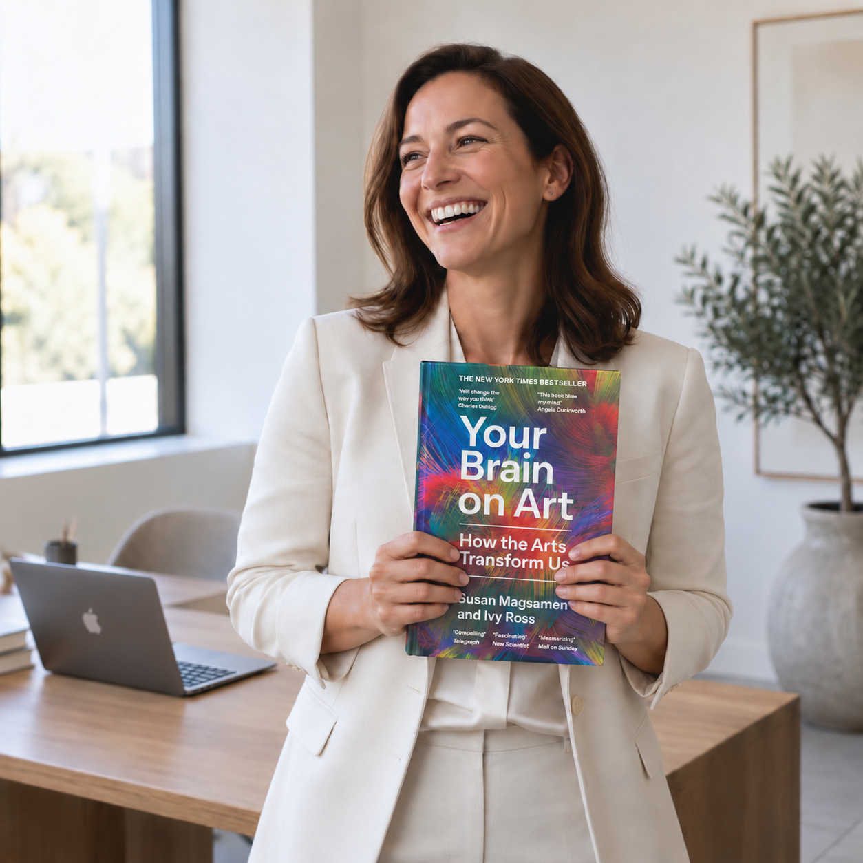 Autora sonriente con su libro en una oficina moderna y minimalista